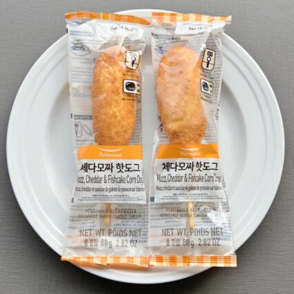 Two Individually Wrapped in Clear Plastic Pulmuone Mozzarella Cheddar Fishcake Corn Dogs on a White Plate